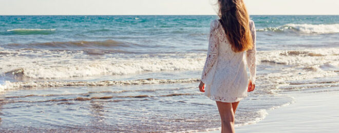 綺麗な女性が海沿いを歩いている